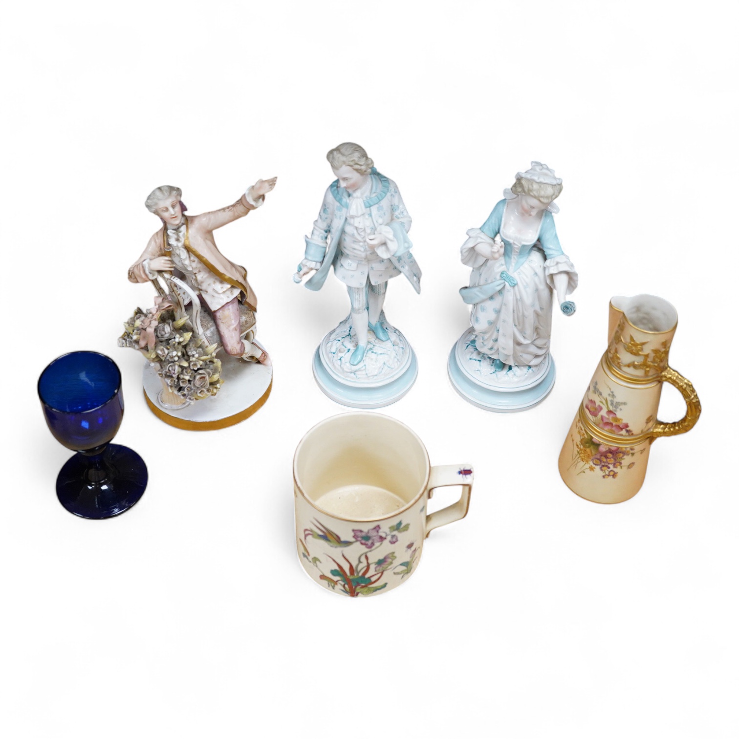 Sundry porcelain comprising three German figures, a Royal Worcester blush ivory ewer and a mug, together with a blue wine glass, largest 26cm high